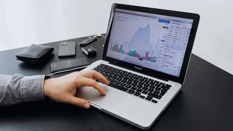 Main sur le pavé tactile d'un ordinateur portable affichant des graphiques financiers