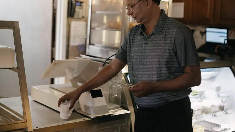 Commerçant tenant des billets près d'une caisse enregistreuse au comptoir d'un café