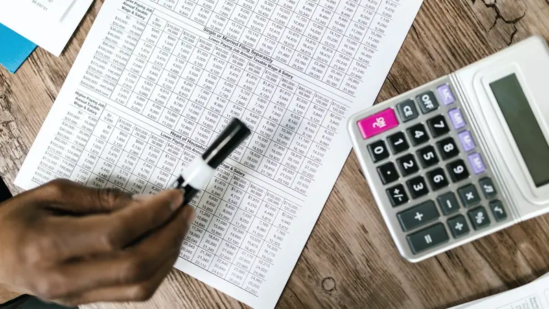 Main tenant un surligneur au-dessus d'un barème fiscal imprimé, à côté d'une calculatrice