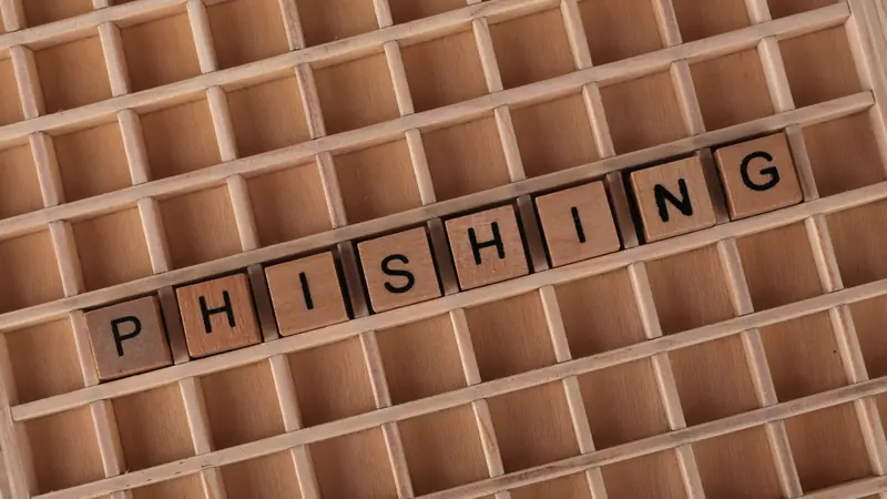 Lettres en bois formant le mot phishing dans une grille en bois