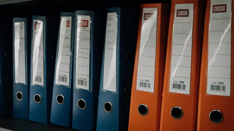 Classeurs à levier bleus et orange alignés sur une étagère de bureau