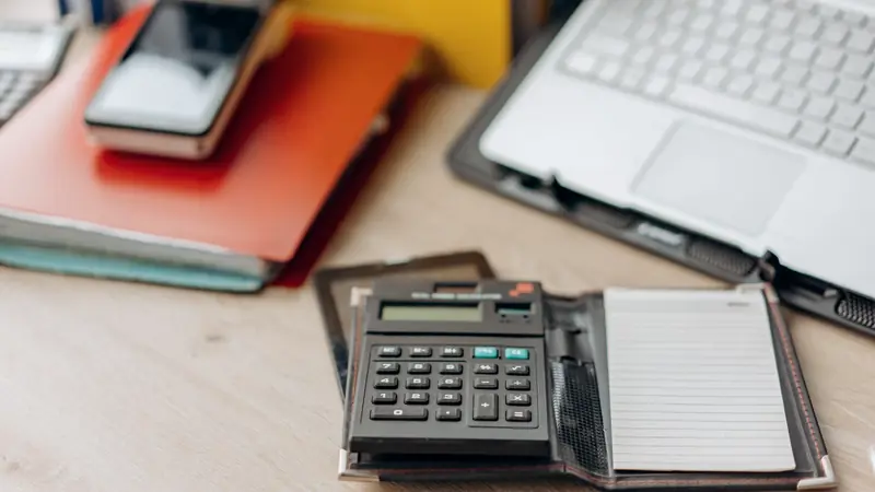 Calculatrice, carnet, ordinateur portable et téléphone sur un bureau