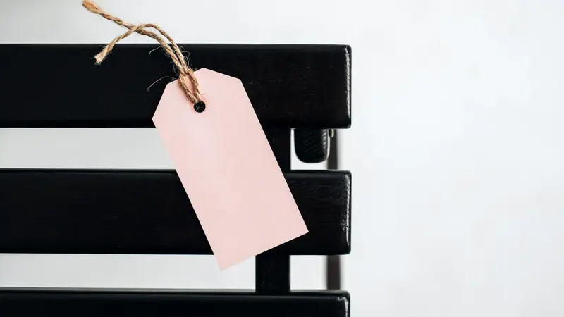 Étiquette de prix vierge suspendue au dossier d'une chaise noire