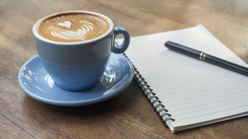Tasse de café et carnet ouvert avec un stylo sur une table en bois
