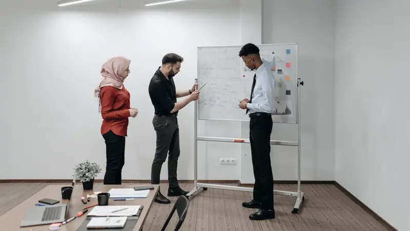 Équipe réunie devant un tableau blanc dans une salle de réunion lumineuse