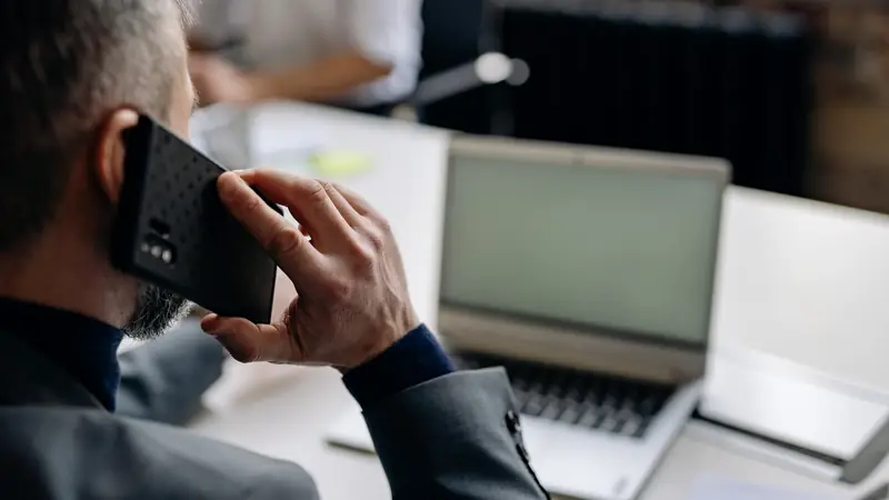 Homme au téléphone devant un ordinateur portable dans un bureau