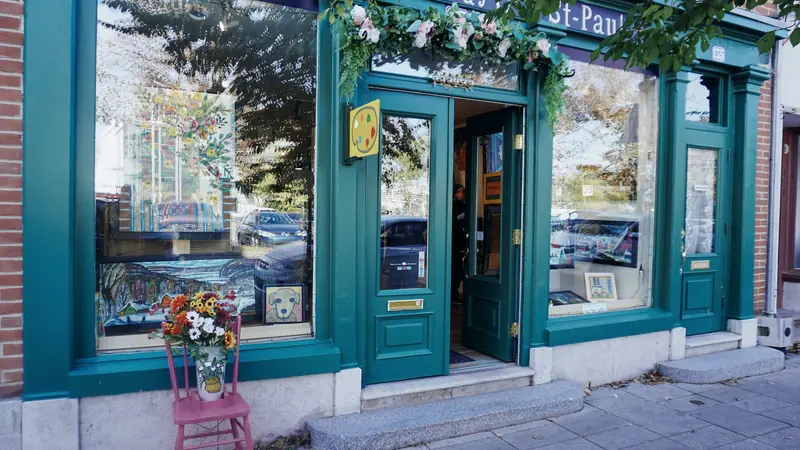 Devanture bleu canard d'une boutique de quartier avec des fleurs devant l'entrée