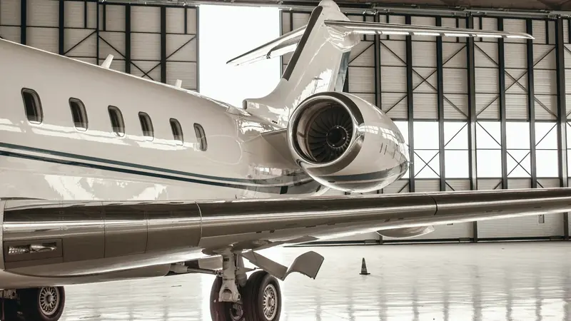 Jet d'affaires blanc stationné dans un hangar, vue arrière sur le réacteur et l'aile