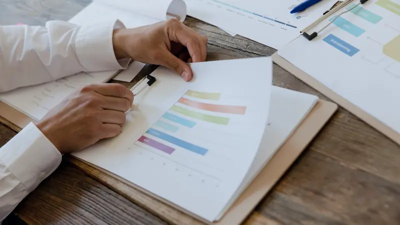 Mains comparant des documents imprimés avec des graphiques sur un bureau en bois