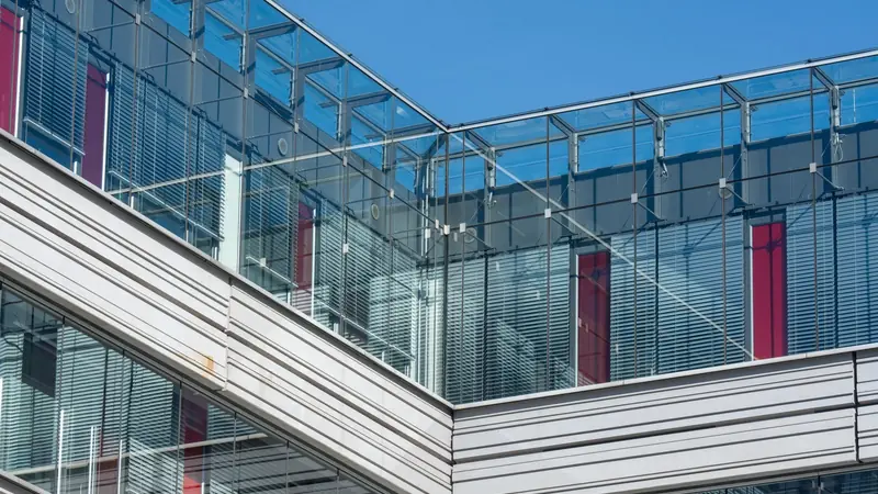 Angle d'un immeuble de bureaux contemporain en verre et pierre claire sous un ciel bleu