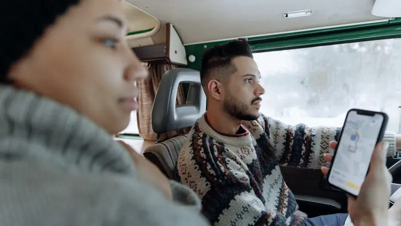 Passagère et conducteur dans un van, un téléphone affichant une carte de navigation à la main